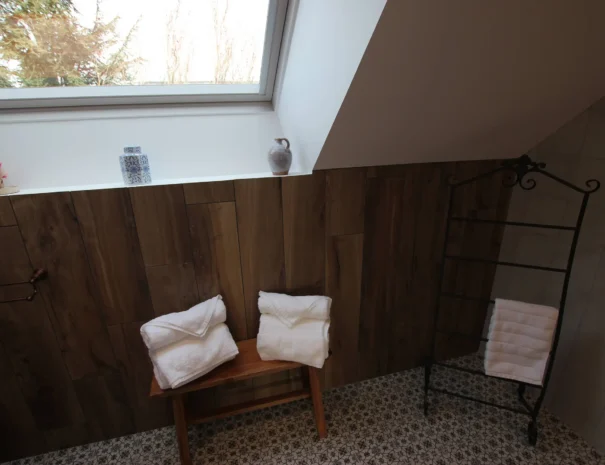 Coin salle de bain soigné au Domaine de Champouteau, serviette enroulée et étagère en bois, charme et praticité pour un séjour détente