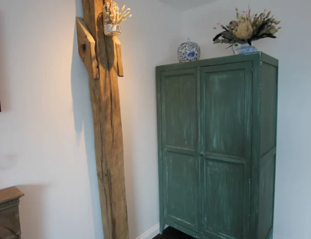 Coin décoratif élégant au Domaine de Champouteau, armoire vintage verte et étagère en bois brut, ambiance chaleureuse et créative