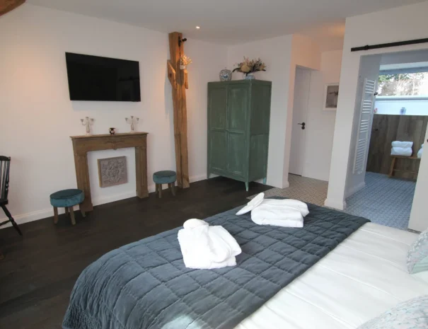 Suite spacieuse au Domaine de Champouteau, lit douillet, télévision et armoire vintage verte, confort et style pour un séjour inoubliable