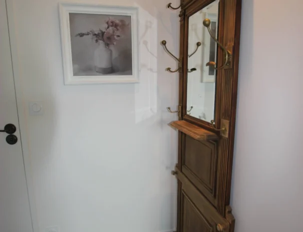 Entrée stylée au Domaine de Champouteau, porte-manteau vintage en bois et miroir, ambiance chaleureuse et pratique