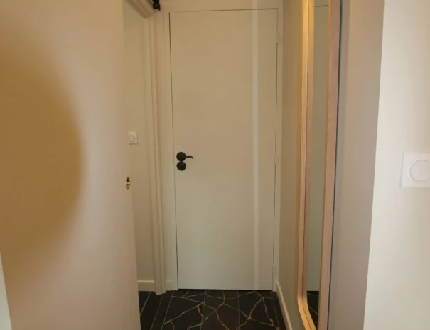 Couloir élégant au Domaine de Champouteau, miroir design et sol en carreaux décoratifs noirs et dorés, ambiance moderne et raffinée