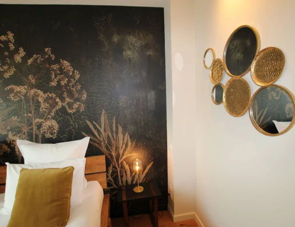 Chambre romantique au Domaine de Champouteau, tête de lit végétale et miroirs dorés, ambiance chaleureuse et élégante pour un séjour inoubliable